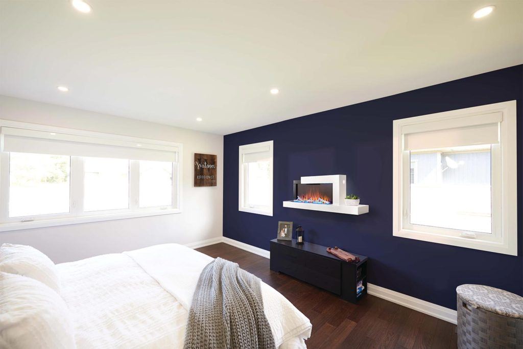 a compact modern electric fireplace with surrounding mantel mounted to a bedroom wall