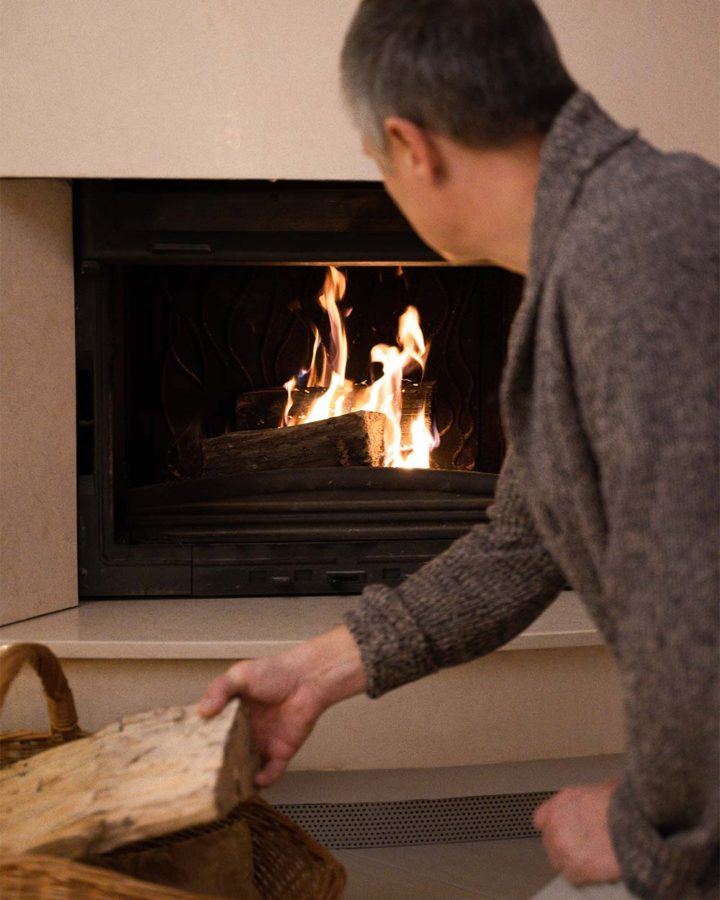 a man putting wood into a burning fireplace